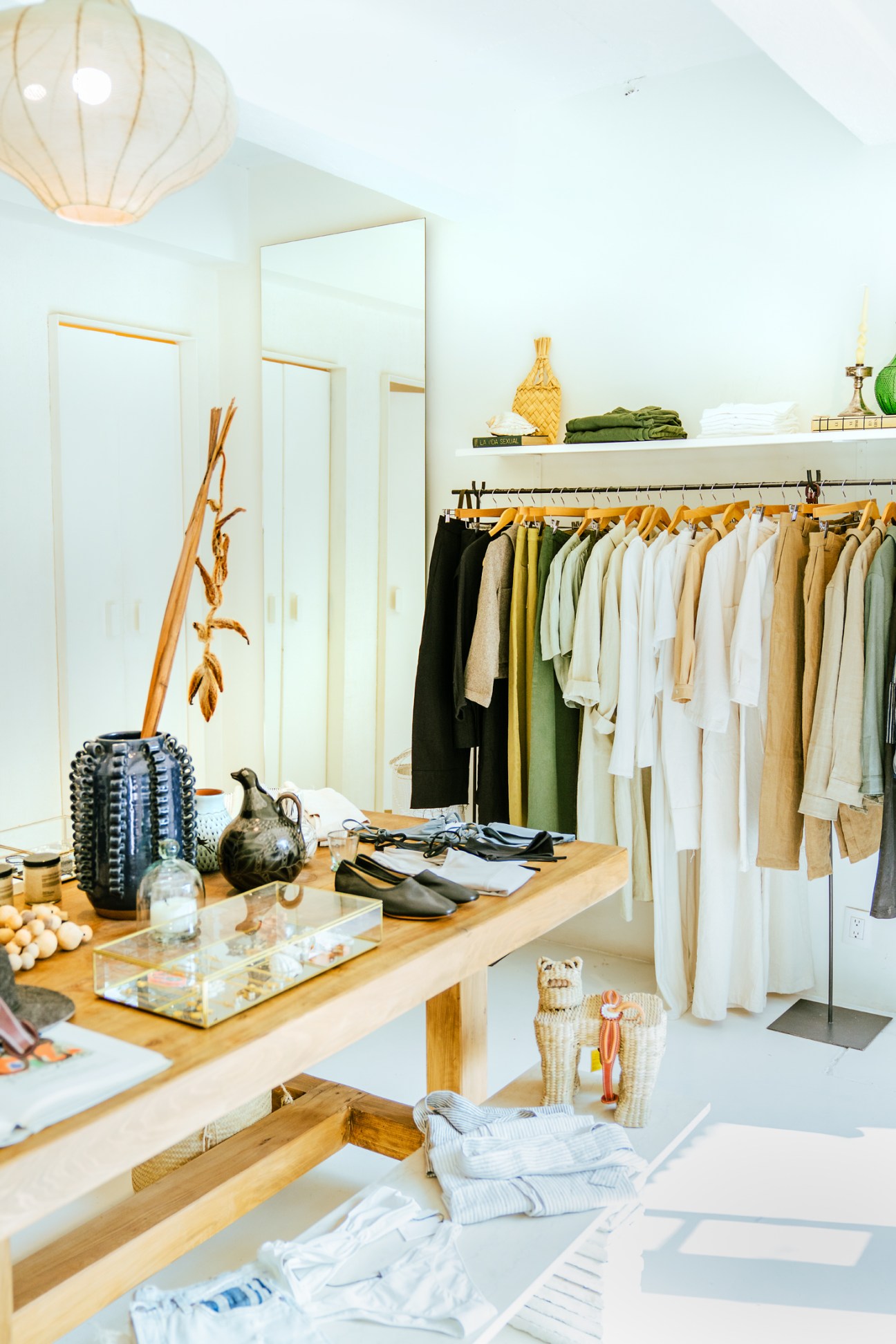 Interior of Zii Ropa clothing store showing bright airy space with clothing racks and wooden display table