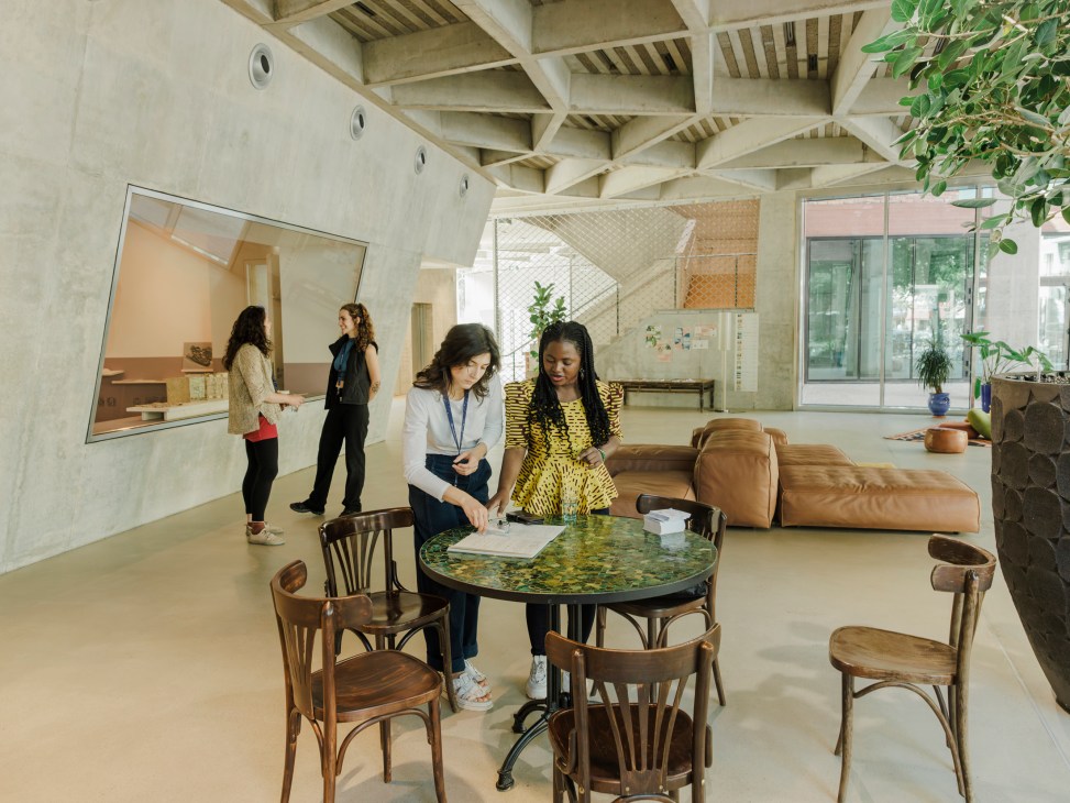 People meeting and working at a round table in Spore House's open interior space with exposed concrete ceiling