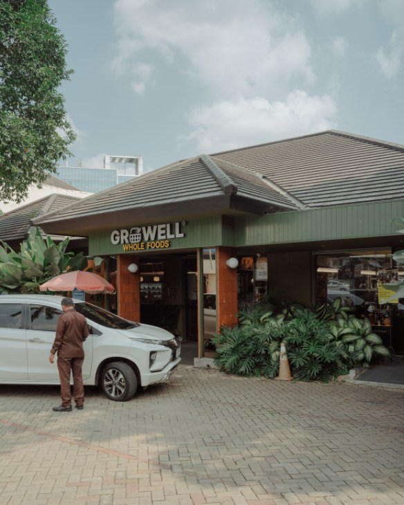 Entrance to Growell store featuring lush green plants and foliage creating a natural welcoming atmosphere
