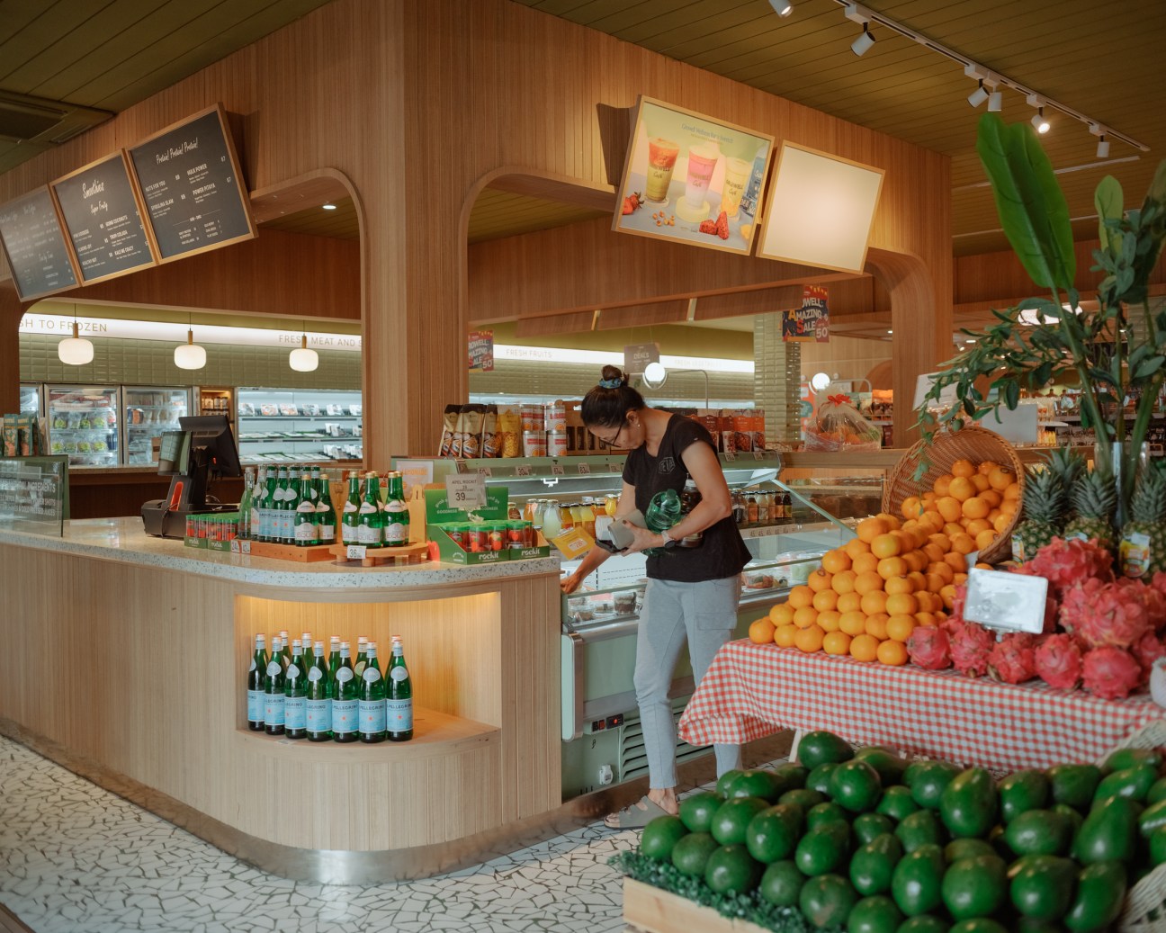 Fresh fruit juices and colorful tropical fruits displayed on wooden counter at Growell grocery store
