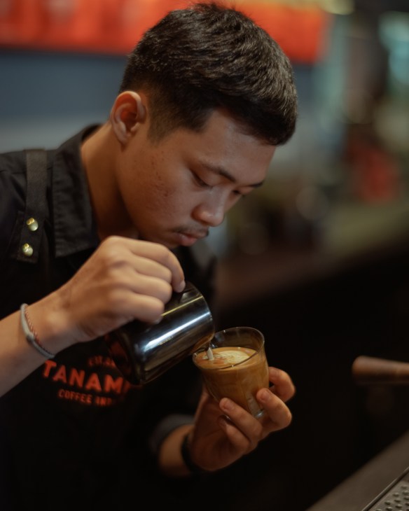 Skilled barista preparing specialty coffee using professional espresso machine at Tanamera Coffee shop