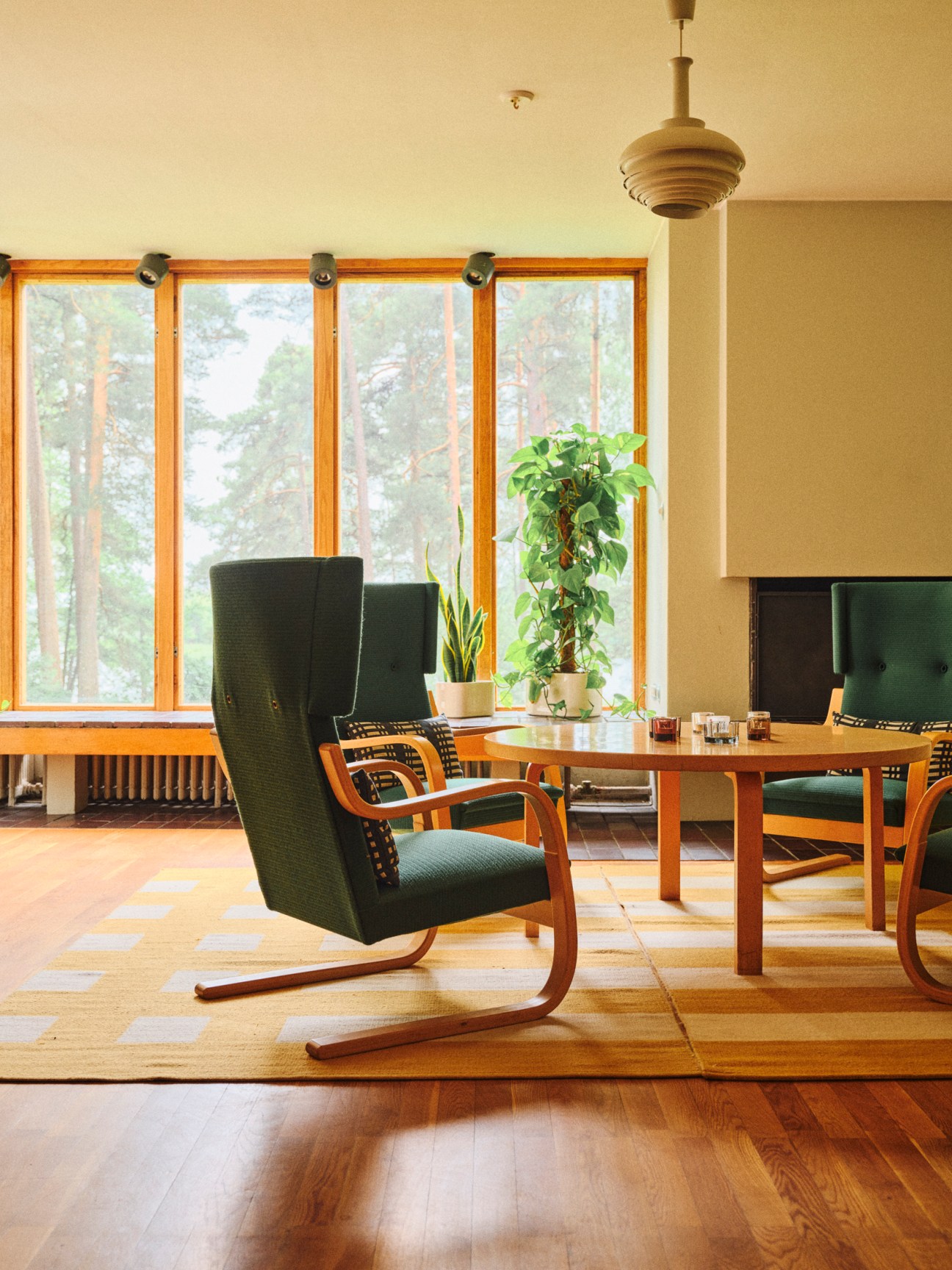 Classic Artek furniture pieces including bent wood chairs and table with distinctive L-shaped legs in white interior
