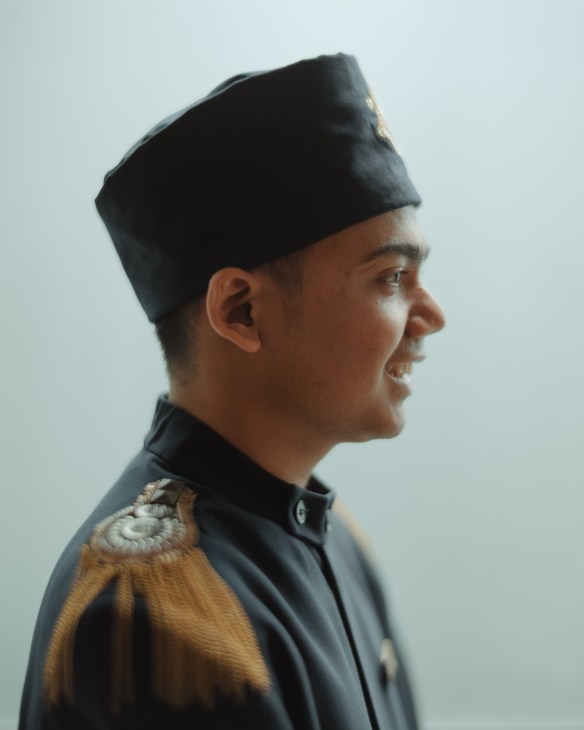 Hotel bellboy in crisp uniform standing at attention in The Gunawarman hotel lobby, representing quality service standards