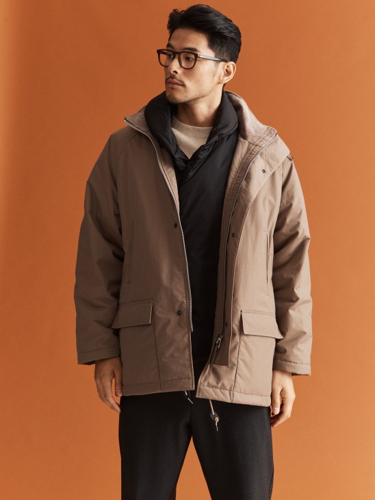 Model in layered jacket and vest with glasses