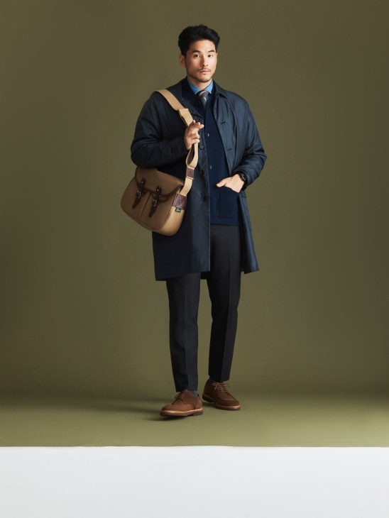 Model in formal overcoat and suit with leather bag
