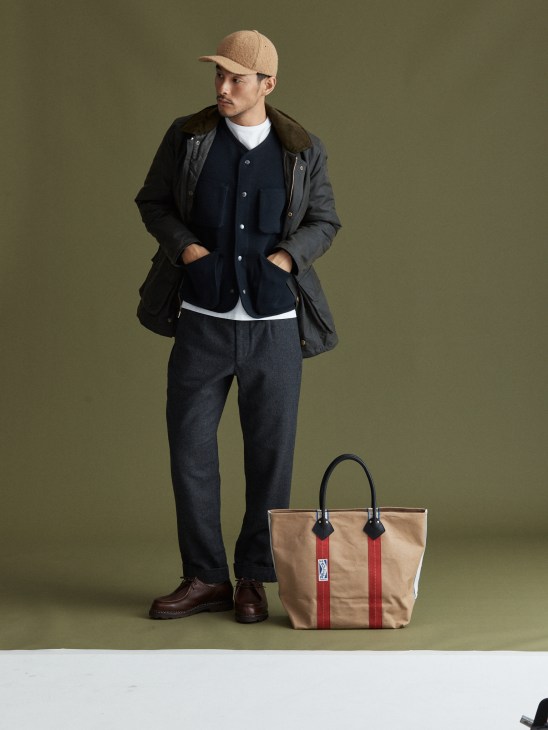 Model with red cap holding phone and bag