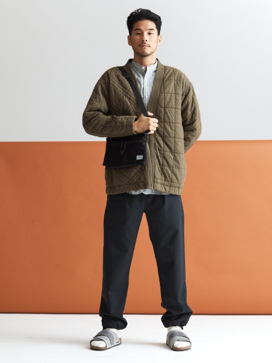 Model in outdoor technical jacket with bag and sandals