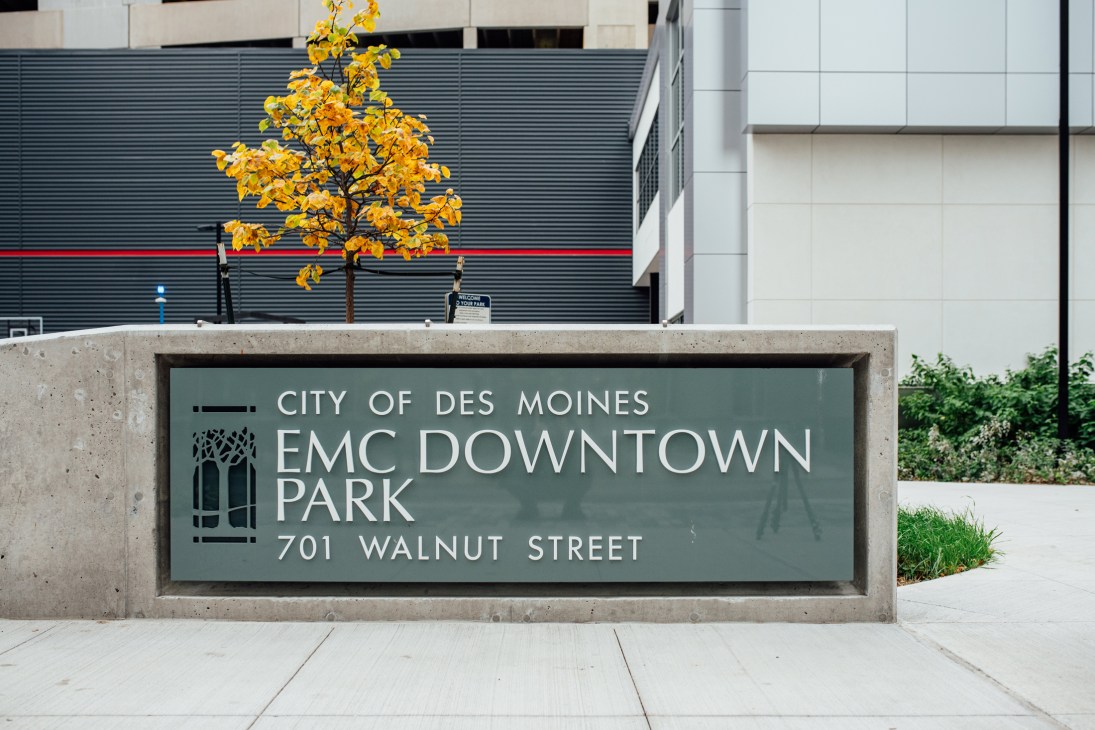 EMC Downtown Park sign with yellow autumn tree and modern building facade in Des Moines