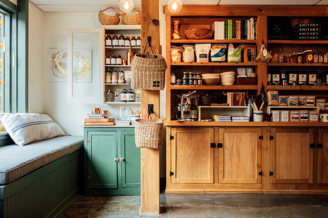 Interior of Des Moines Mercantile retail shop with wooden shelving, green storage cabinets, and artisanal products on display.