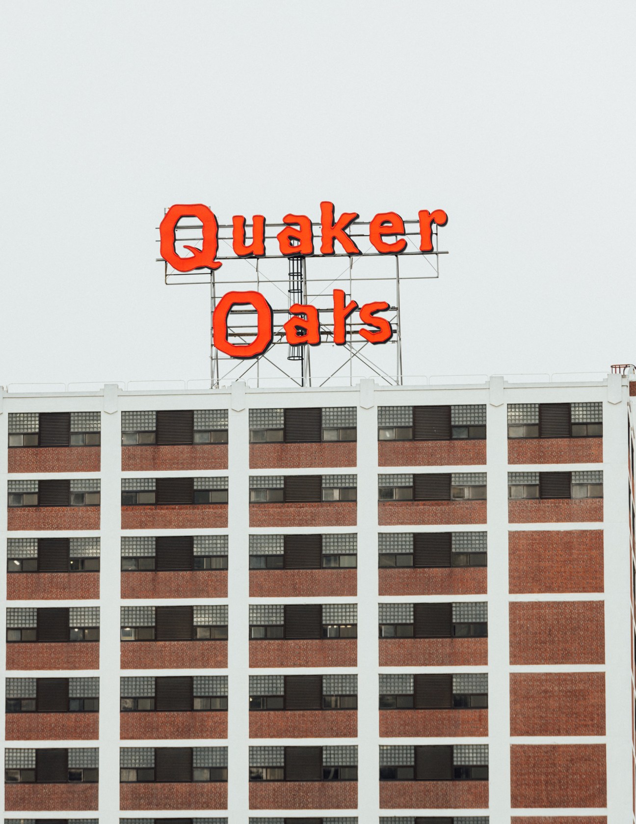 Red vintage Quaker Oats neon sign atop a large brick industrial building in Cedar Rapids.