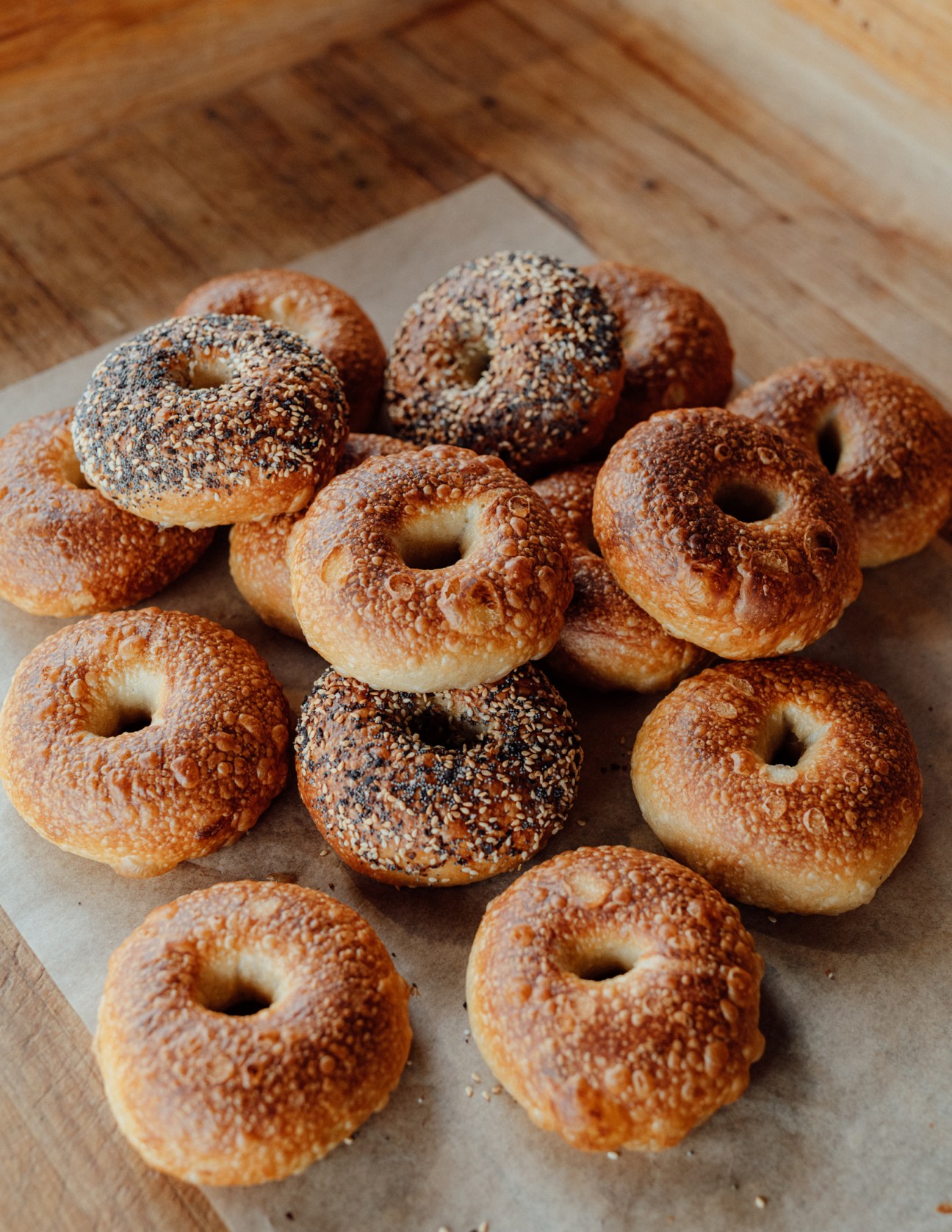 Assorted bagels with sesame and poppy seed toppings on parchment paper.