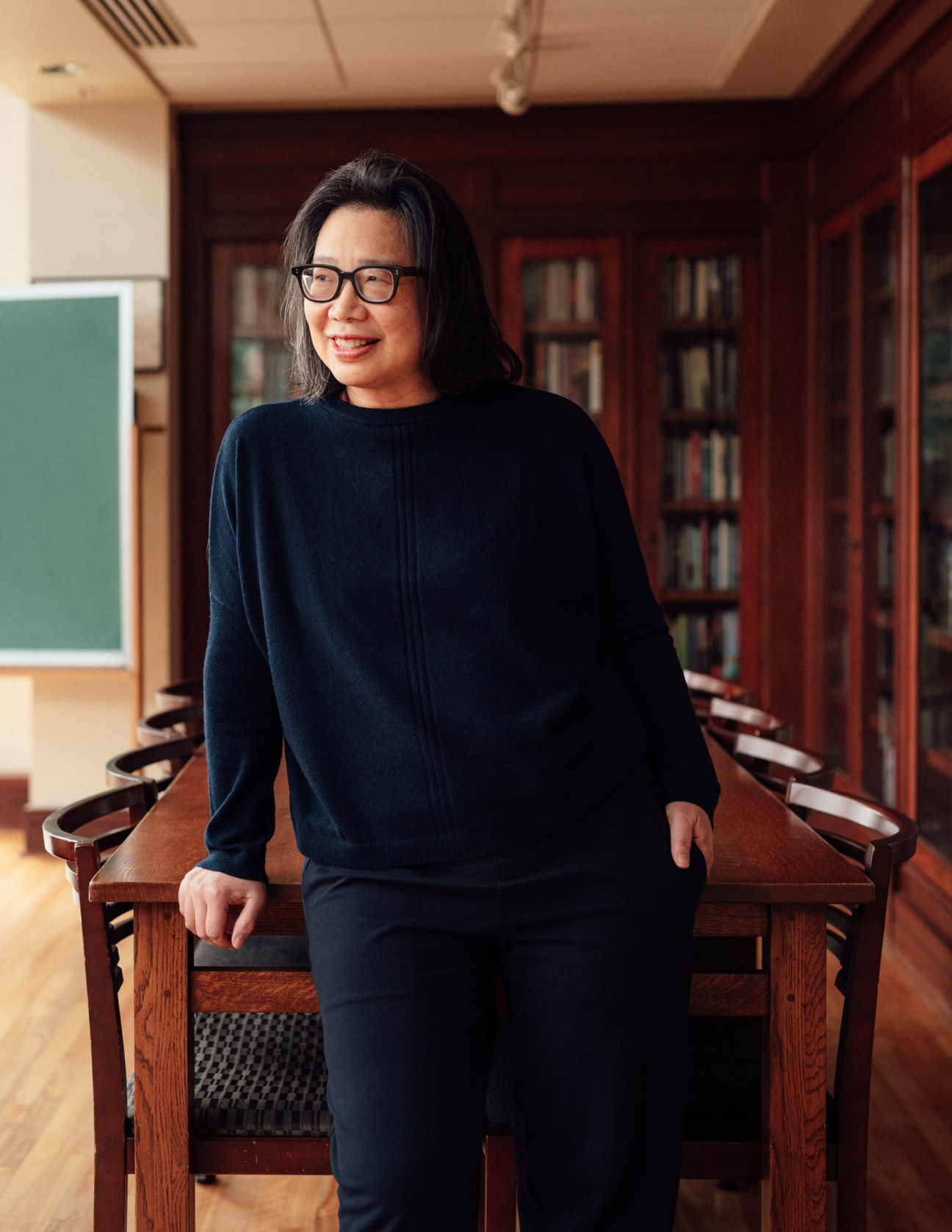 Lan Samantha Chang, director of the University of Iowa Writers' Workshop, stands in a library room with bookshelves behind her.
