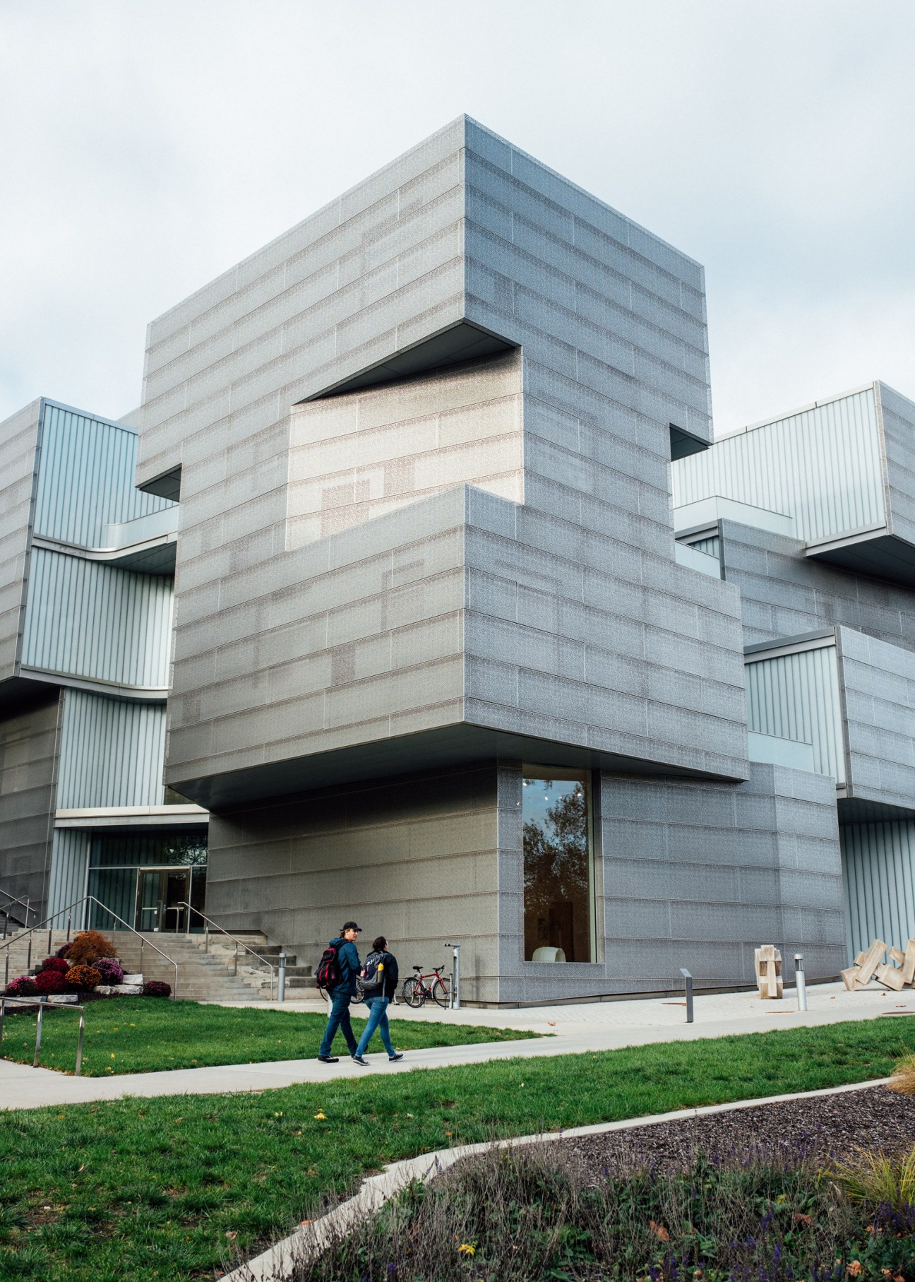 Modern concrete and glass Visual Arts Building at University of Iowa with students walking on campus grounds.