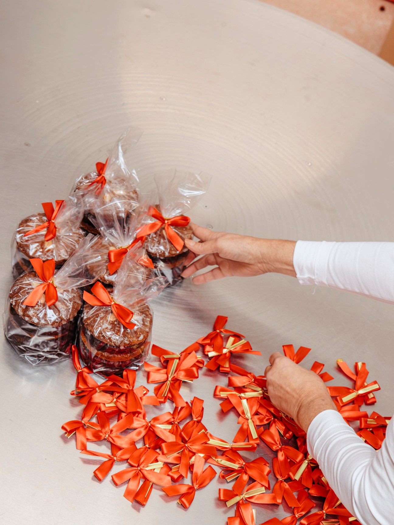 Hands packing Lebkuchen gingerbread tied with red ribbons into boxes at Lebküchnerei Woitinek bakery.