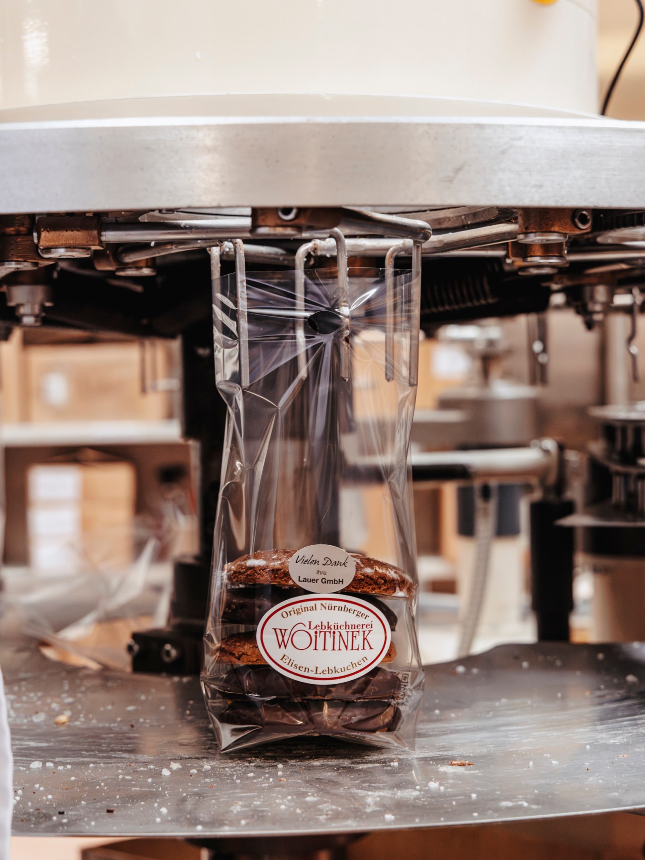 Packaged Lebkuchen gingerbread from Lebküchnerei Woitinek with red ribbon and label on production equipment.