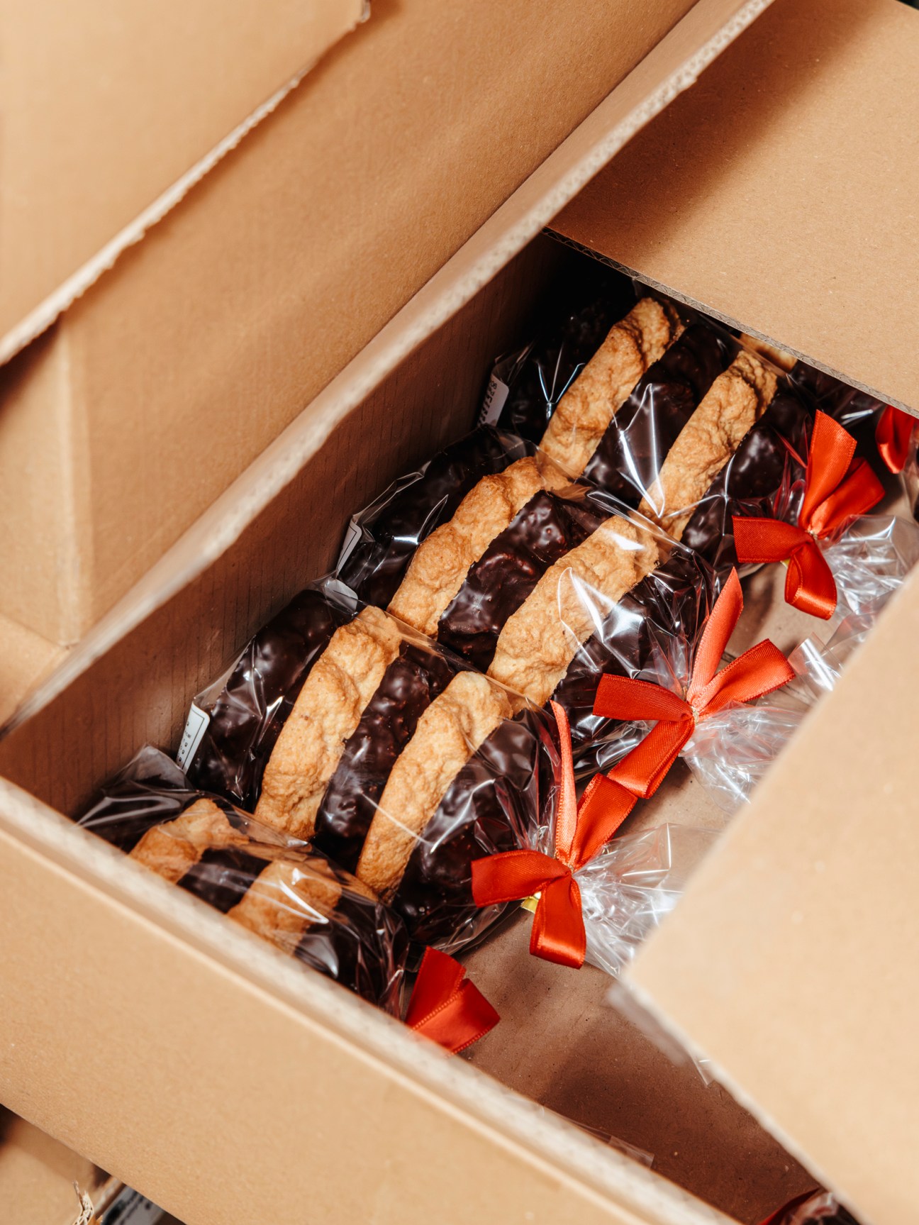 Packaged Lebkuchen gingerbread cakes with red ribbons arranged in a cardboard box.
