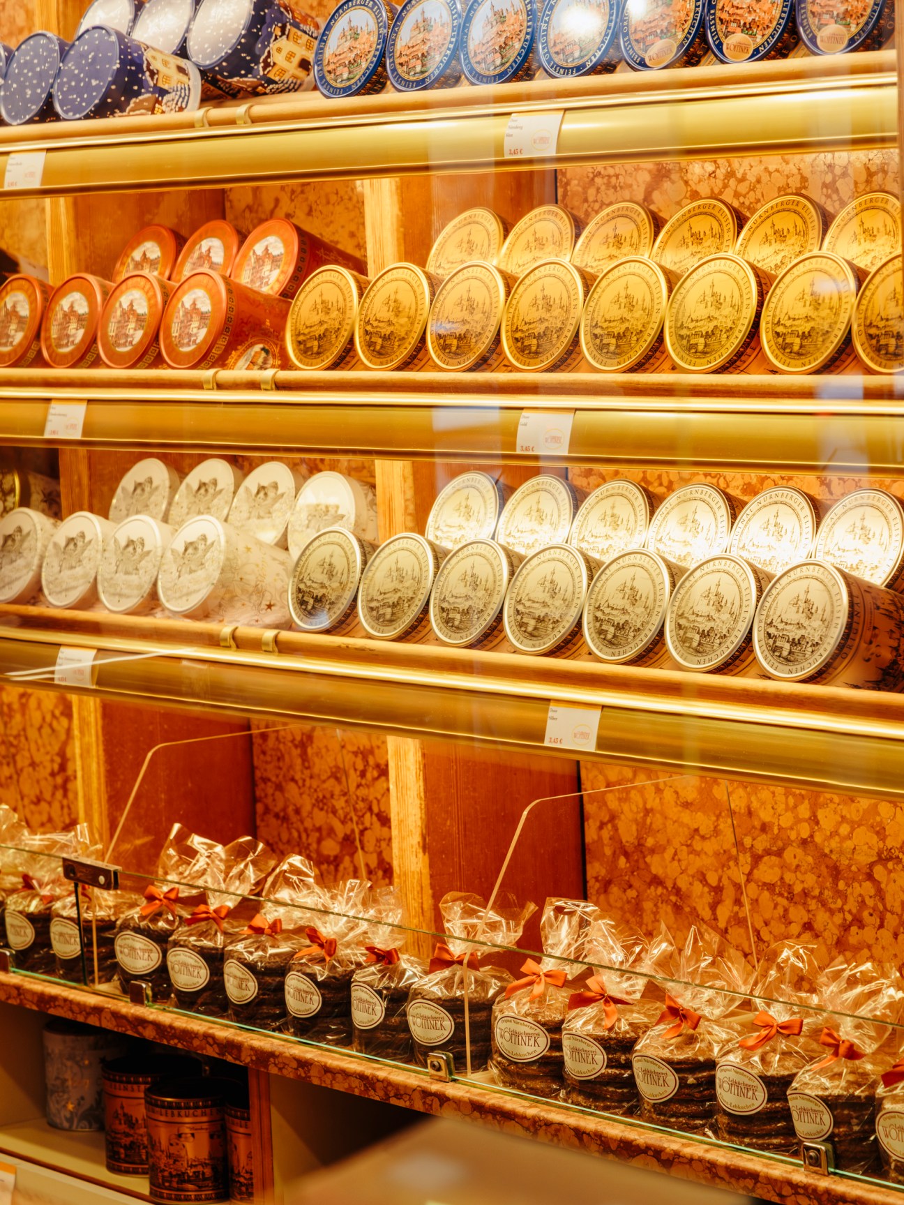 Display shelves of packaged Lebkuchen gingerbread with decorative plates and red ribbon bows at Lebküchnerei Woitinek in Nuremberg.