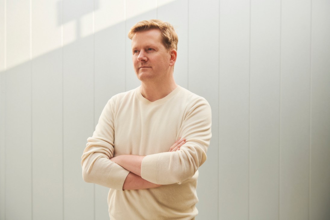 Architect David Thulstrup standing with arms crossed in a bright white interior space