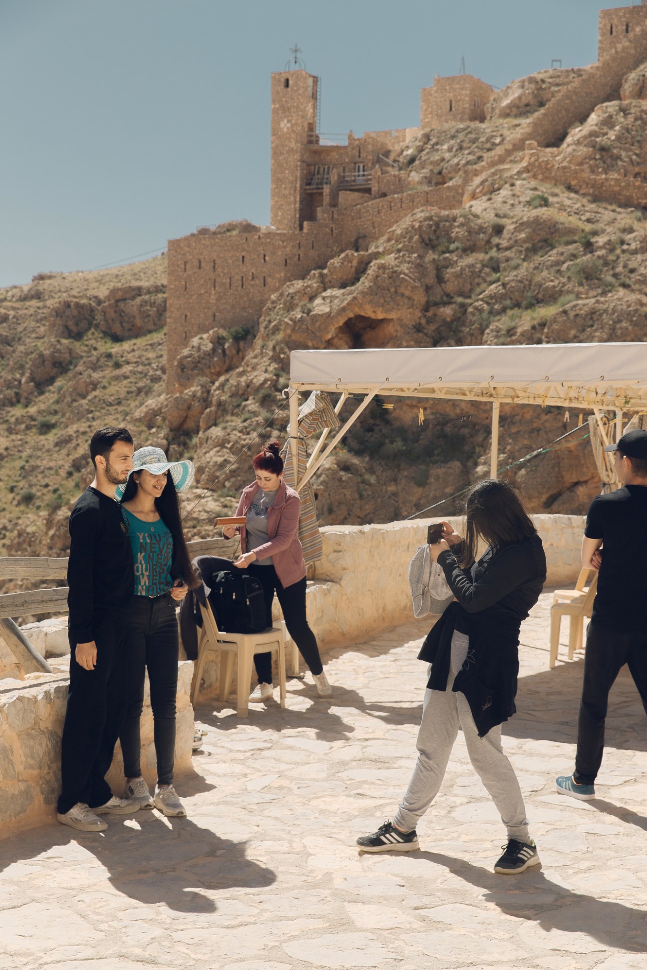 Young people at an archaeological site with ancient stone ruins and fortress structures in the background