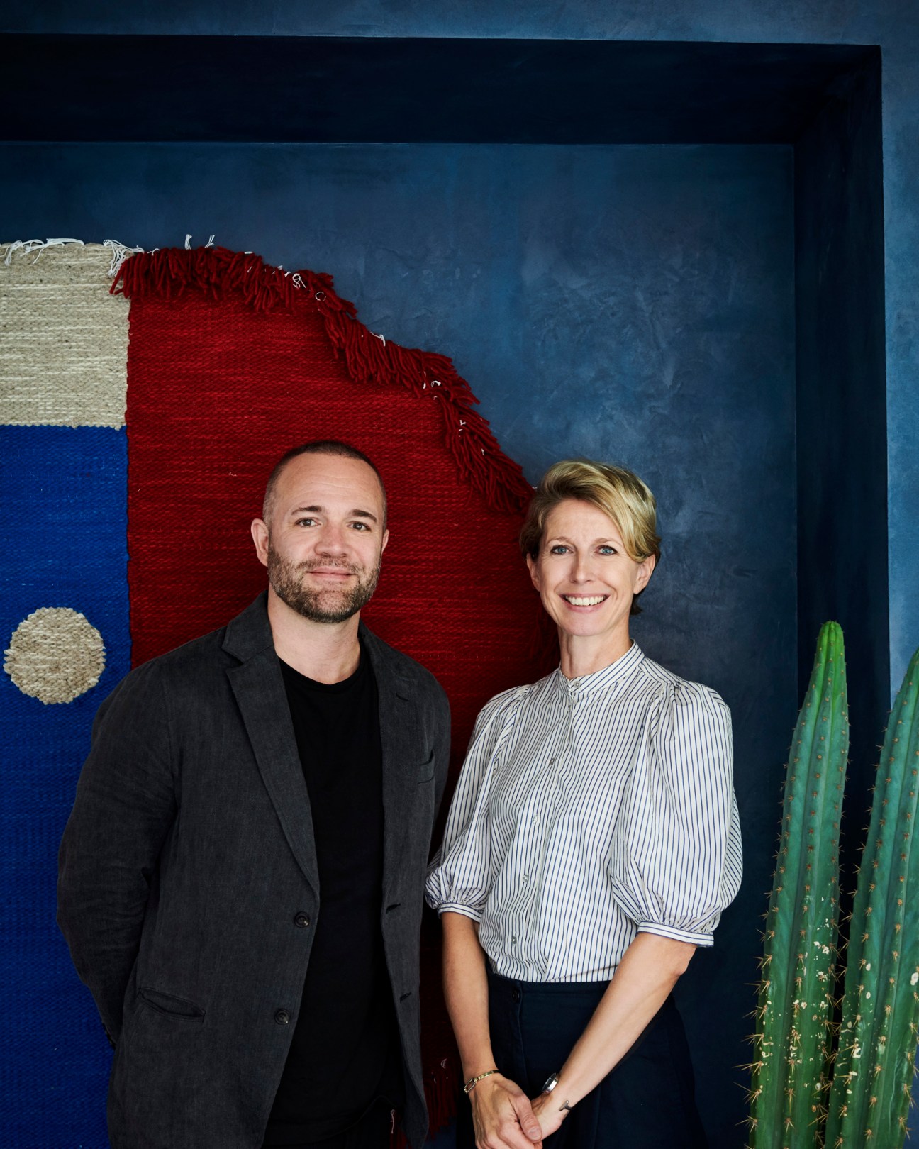 Thomas Lykke and Anne-Marie Buemann standing together in front of colorful textured wall art
