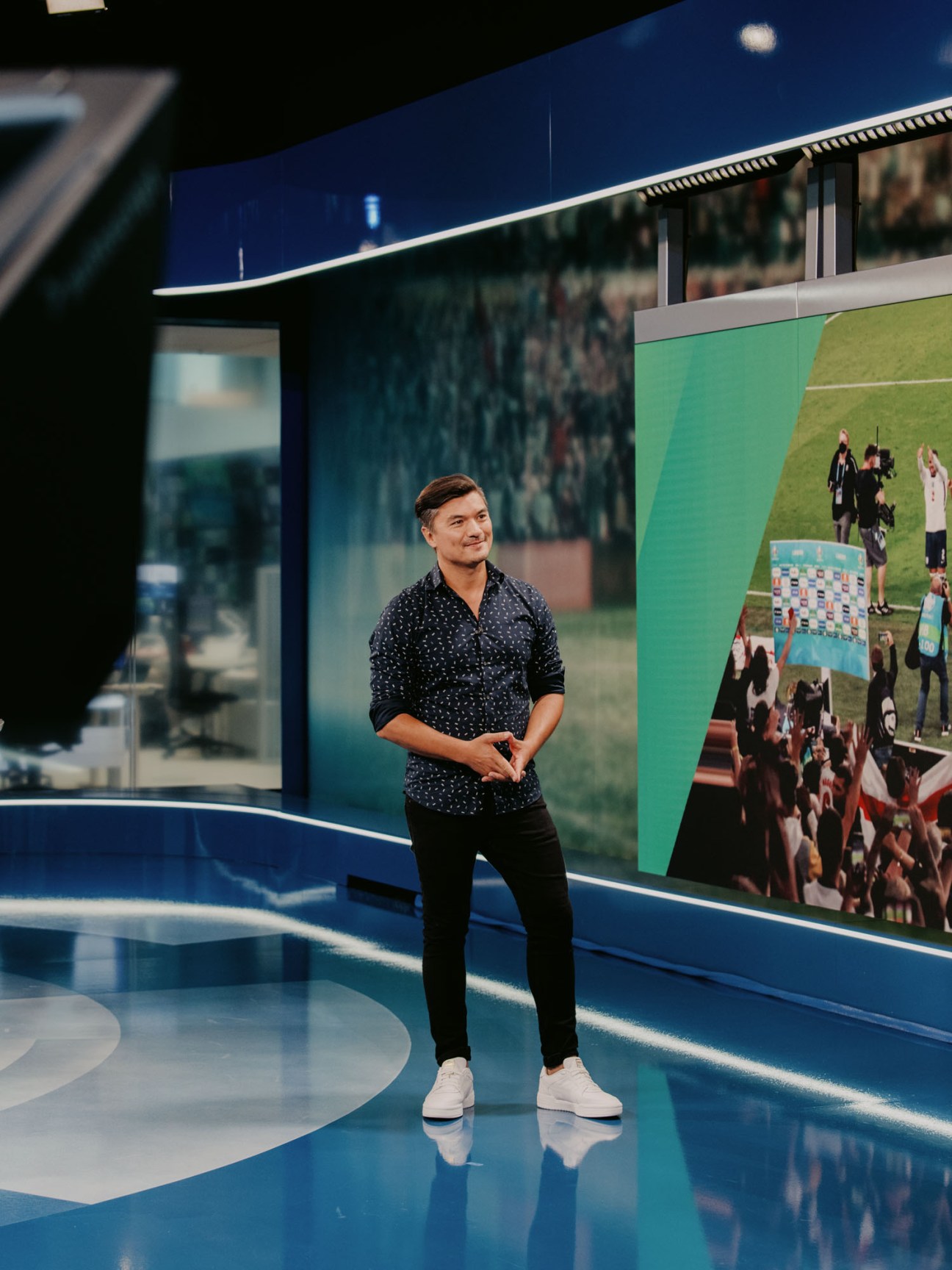 Man in suit presenting sports news in television studio setting