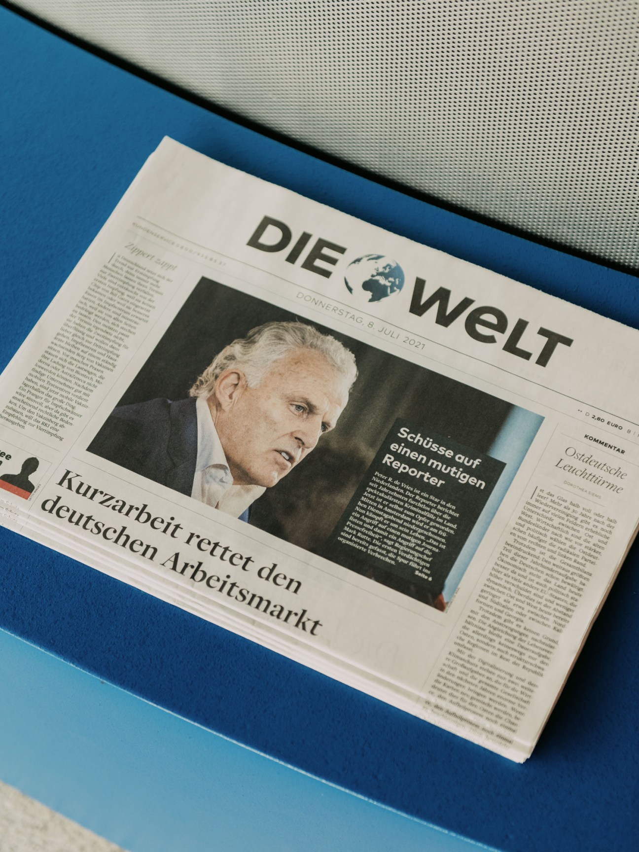 Person reading German newspaper Die Welt in modern office setting
