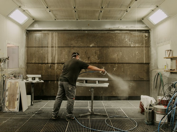 Simone Proietti spray-painting the back panel of a Florence Knoll credenza