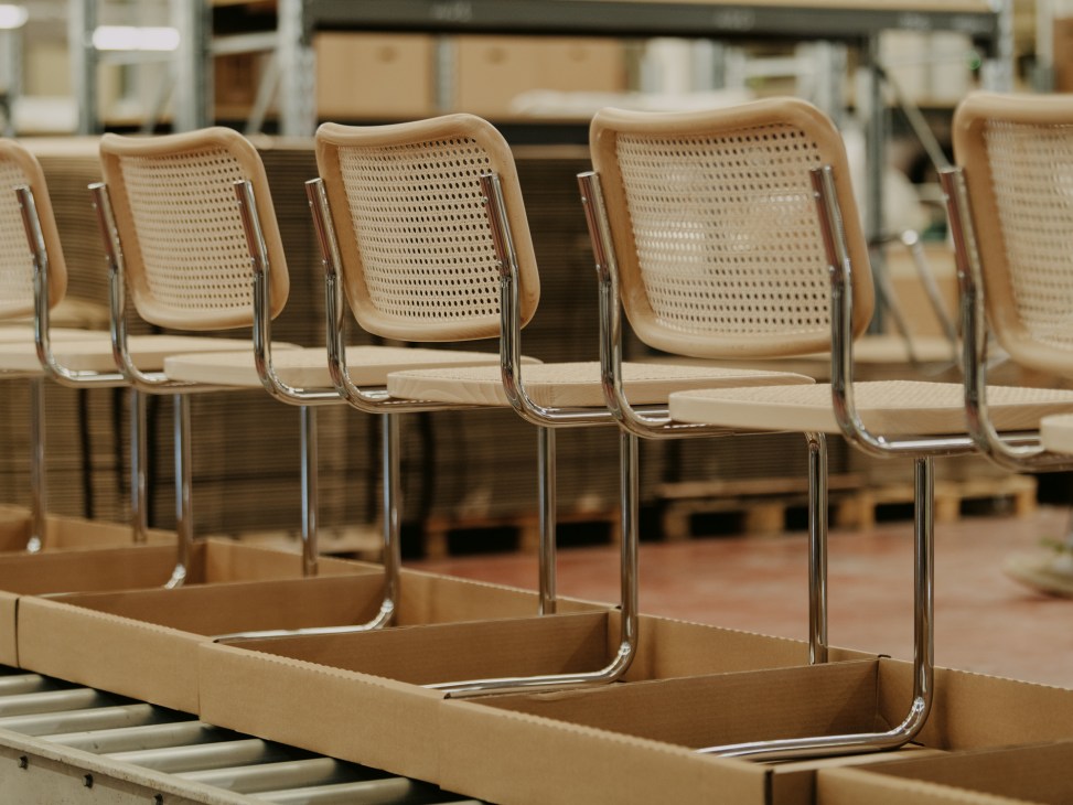 Multiple Cesca chairs by Marcel Breuer with cane backs and chrome cantilever frames stacked in cardboard boxes