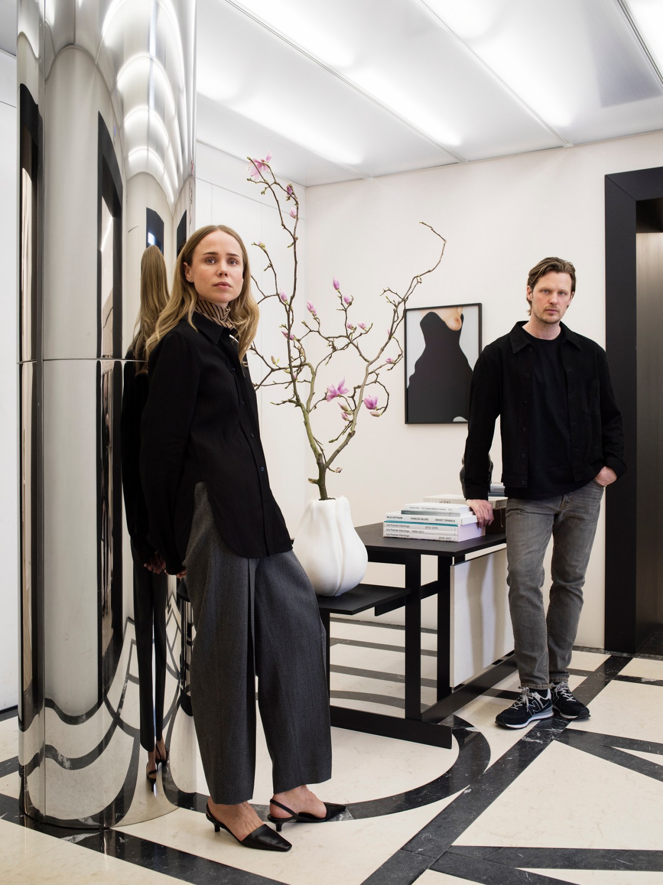Elin Kling and Karl Lindman standing in their modern Stockholm office space with white walls and black accents