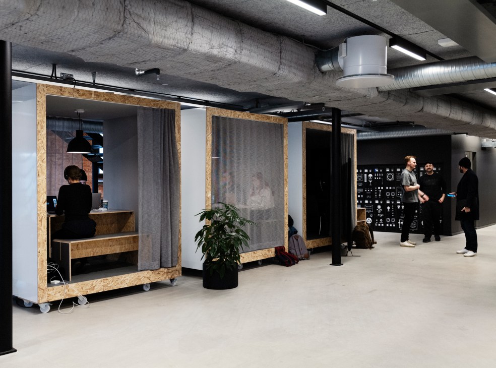 Moveable classrooms with OSB frames and curtains in Berghs School's industrial interior space with exposed ceiling.