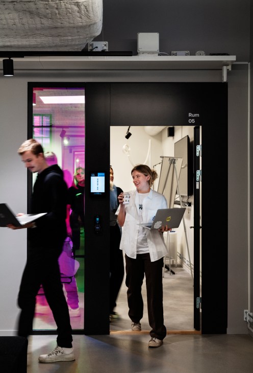 Students exiting a classroom marked 'Rum 05' at Berghs School of Communication.
