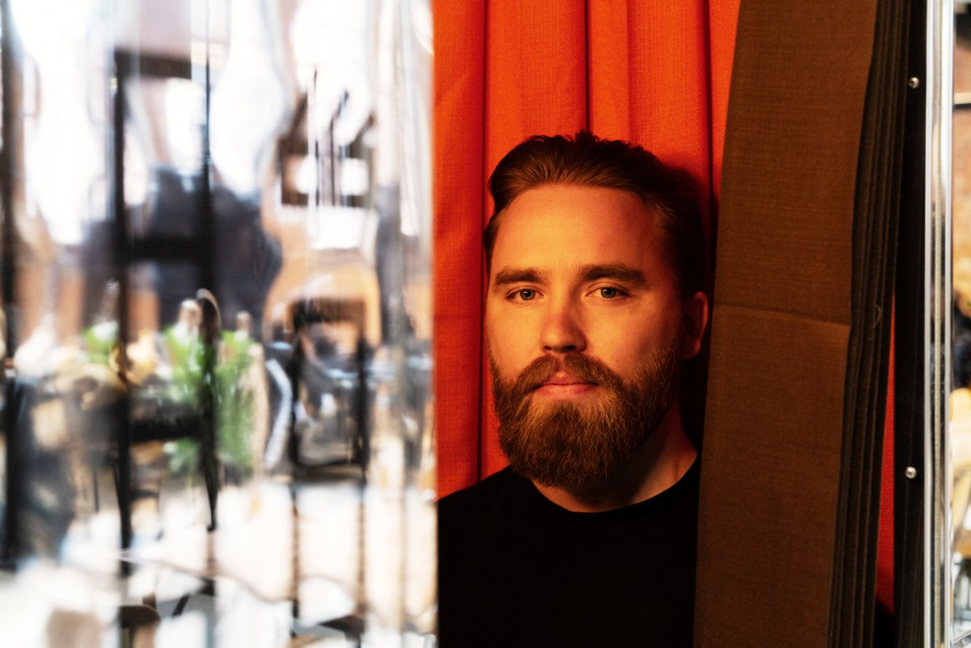 Student Jesper Olofsson poses against a red curtain at Berghs School of Communication.
