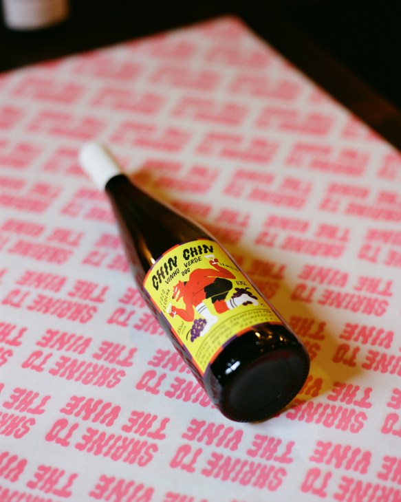 Bottle of Gwin Chin wine with yellow label on pink patterned surface