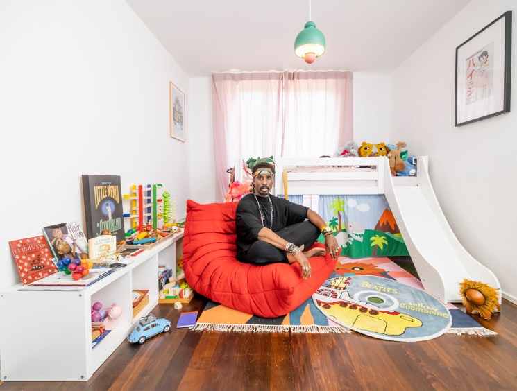 Ini Archibong sitting on a red Togo chair in a colorful child's bedroom
