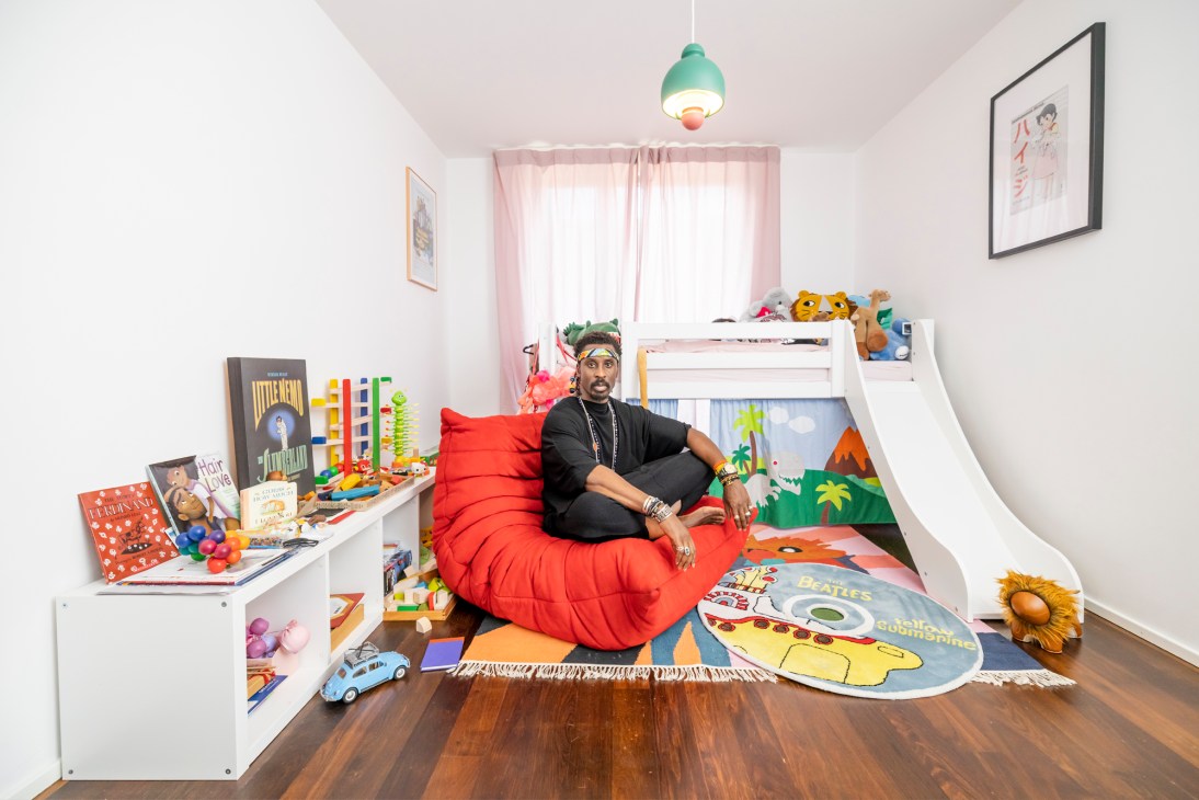 Ini Archibong sitting on a red Togo chair in a colorful child's bedroom