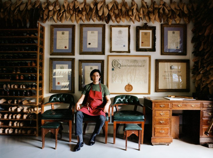 Simon Bolzoni sitting in green leather chairs surrounded by shoe lasts and certificates in the Henry Maxwell workshop