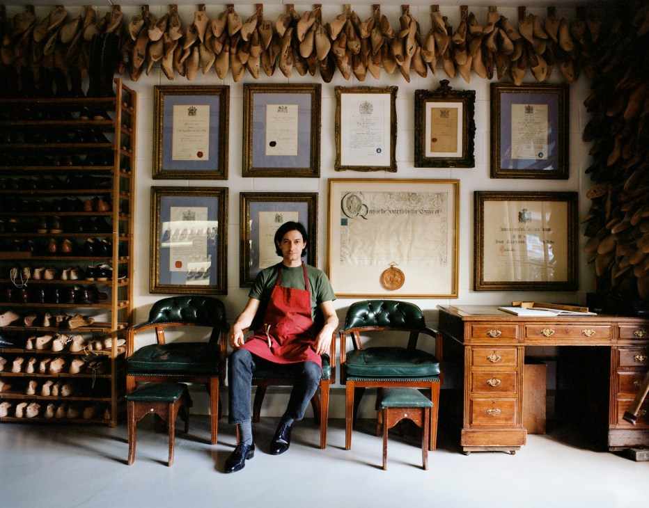 Simon Bolzoni sitting in green leather chairs surrounded by shoe lasts and certificates in the Henry Maxwell workshop