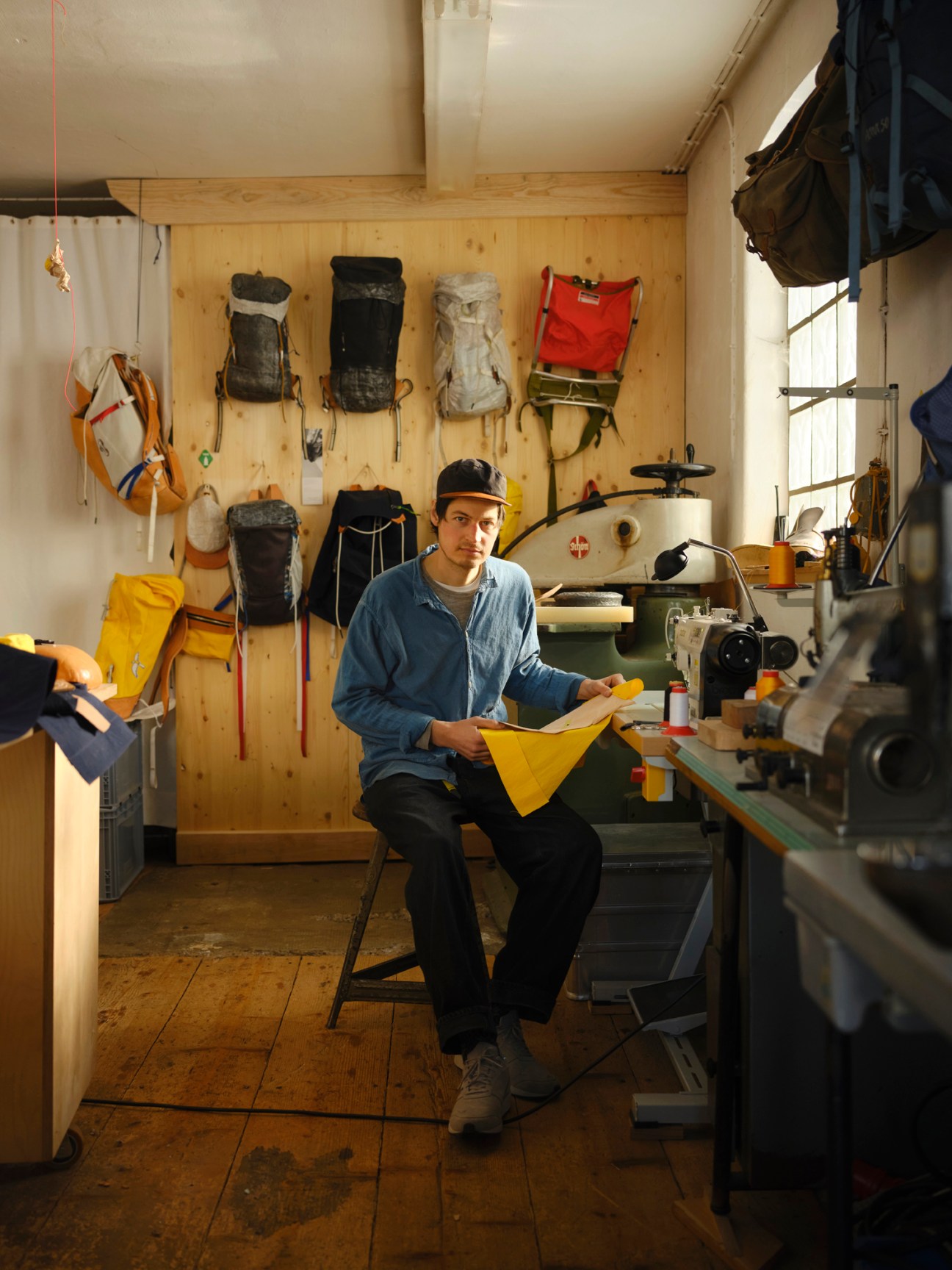 Leander Angerer sitting in his Racing Atelier workshop surrounded by backpacks and equipment