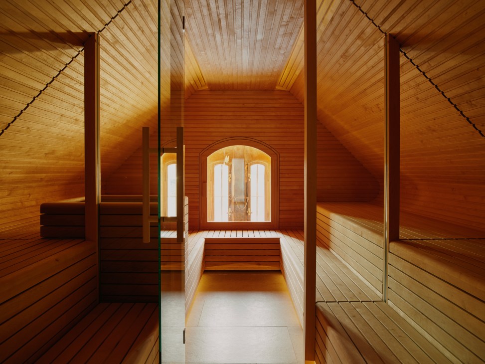 Modern sauna interior with wooden benches, paneled walls and glass door in converted attic space