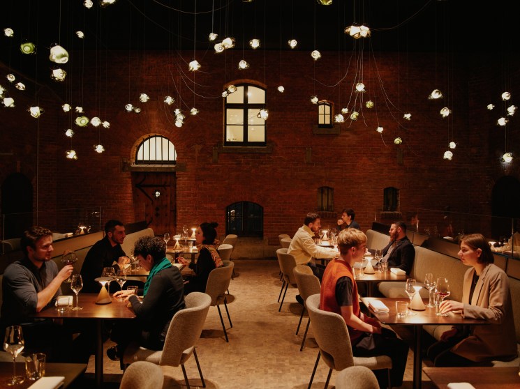 Restaurant dining room with suspended glass pendant lights, brick walls, and diners at tables