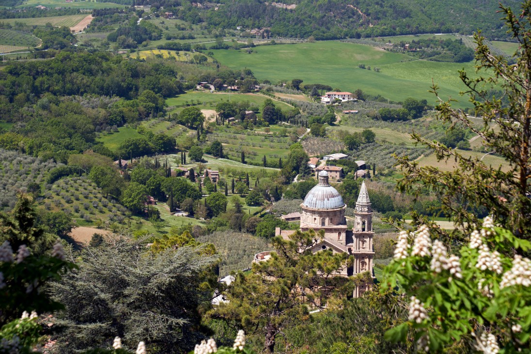 Students studying outdoors on a terrace overlooking rolling Tuscan hills with cypress trees and Renaissance church dome