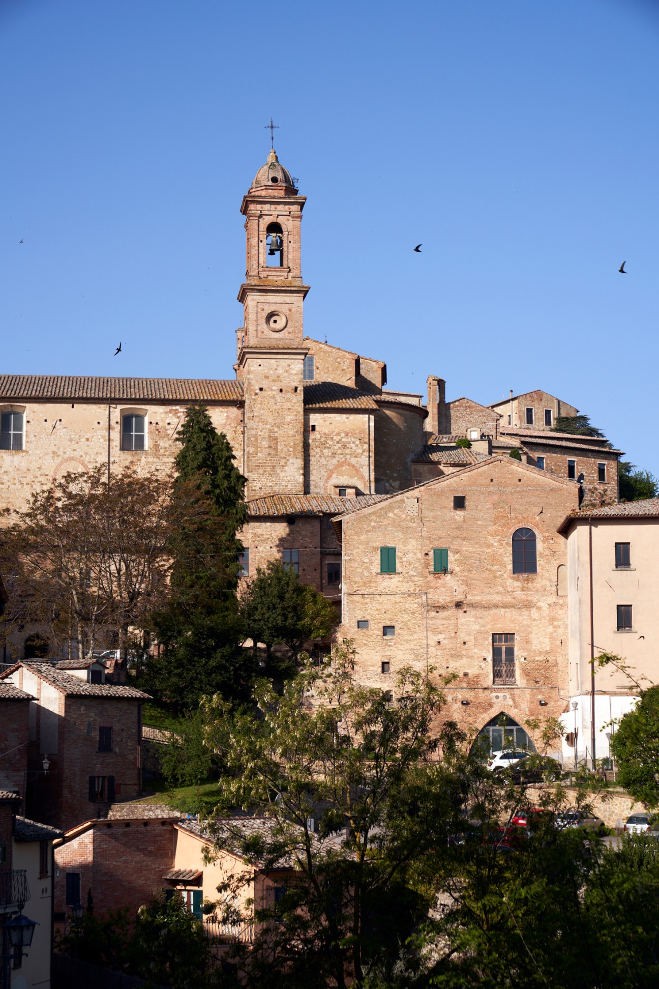 Stone bell tower and historic buildings of Montepulciano against clear blue sky