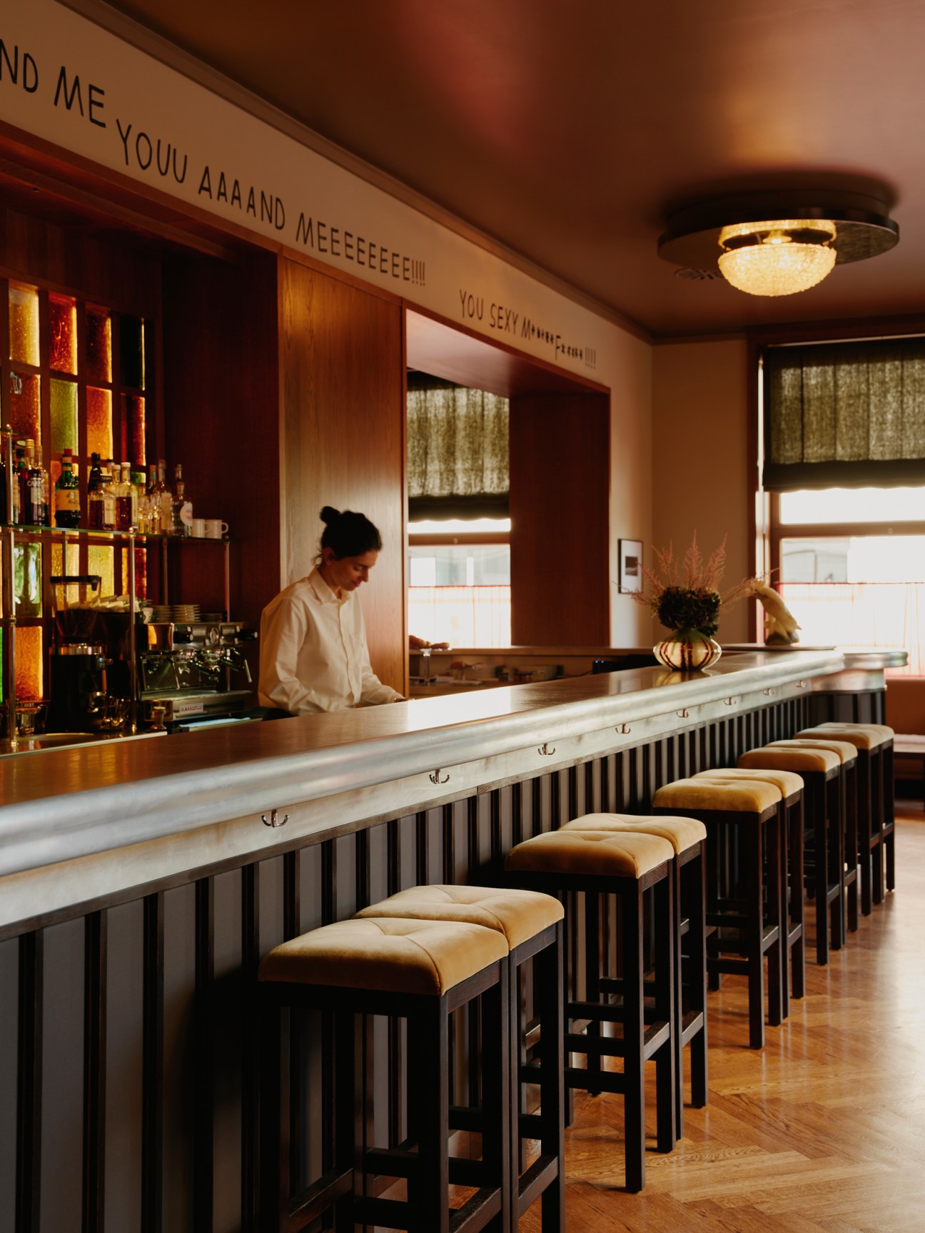 Interior cocktail bar at Château Royal Berlin with long marble counter, bar stools and bartender