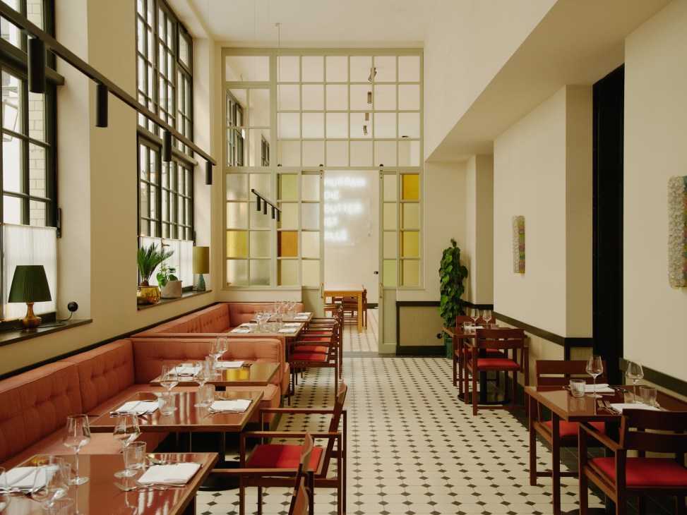 Restaurant interior at Château Royal Berlin with orange banquette seating, geometric floor tiles, and colorful glass partition