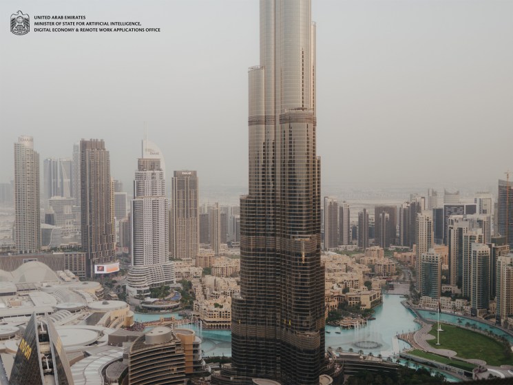 Dubai skyline with high-rise towers and turquoise waterway, featuring UAE AI Office branding.