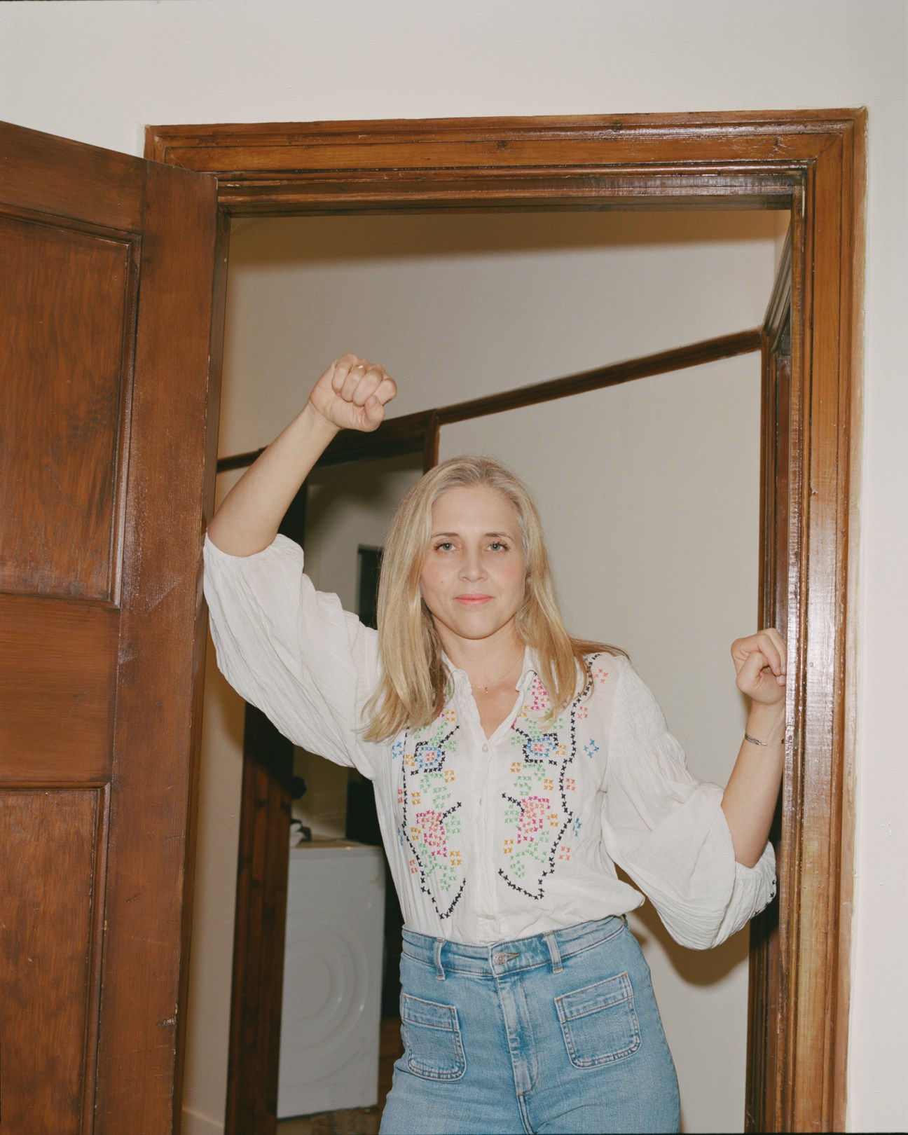 Sarah Balmond making victory gestures with both fists raised while standing in a doorway