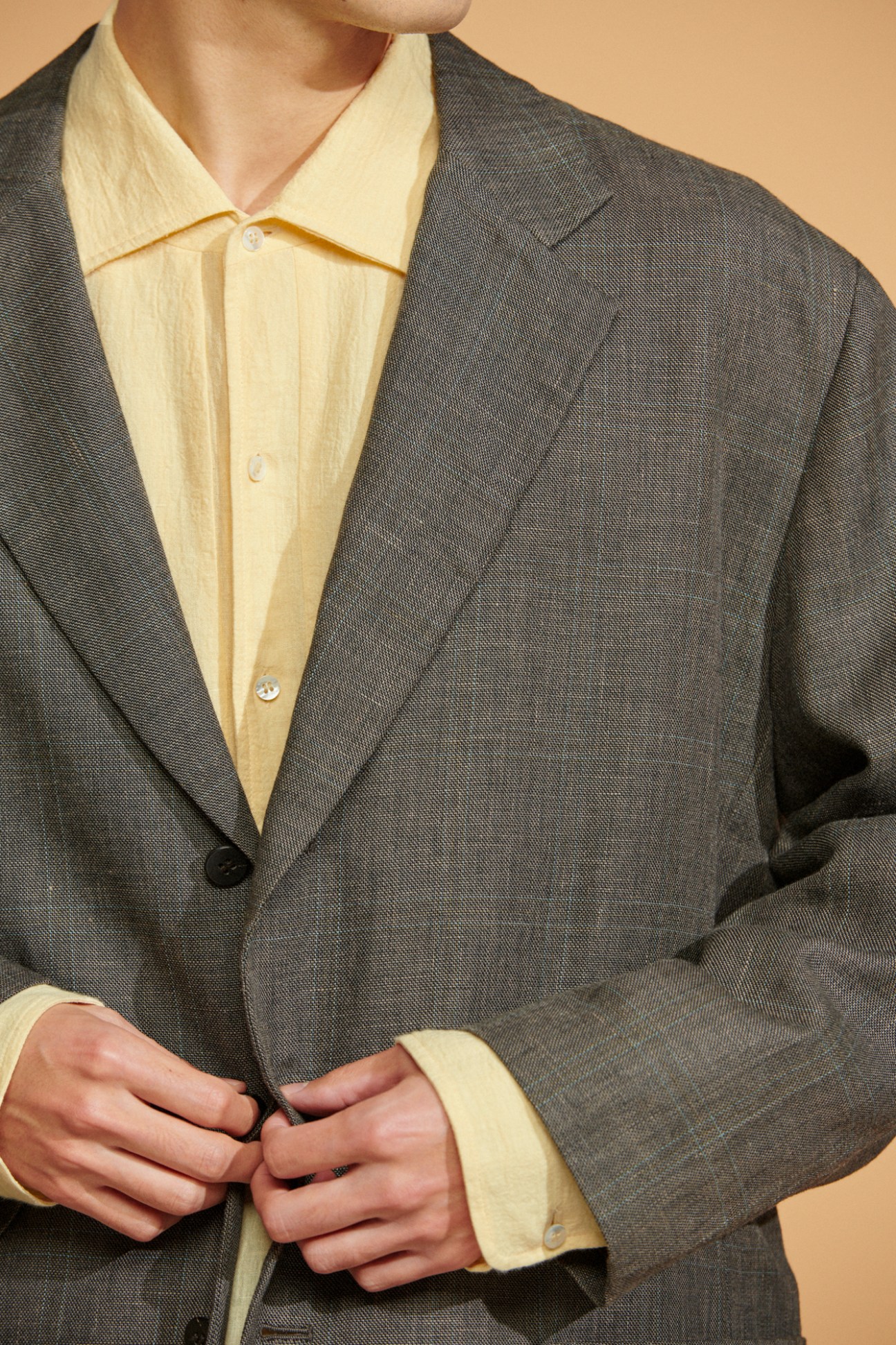 Model wearing grey Cale jacket and yellow shirt showing subtle fabric pattern details