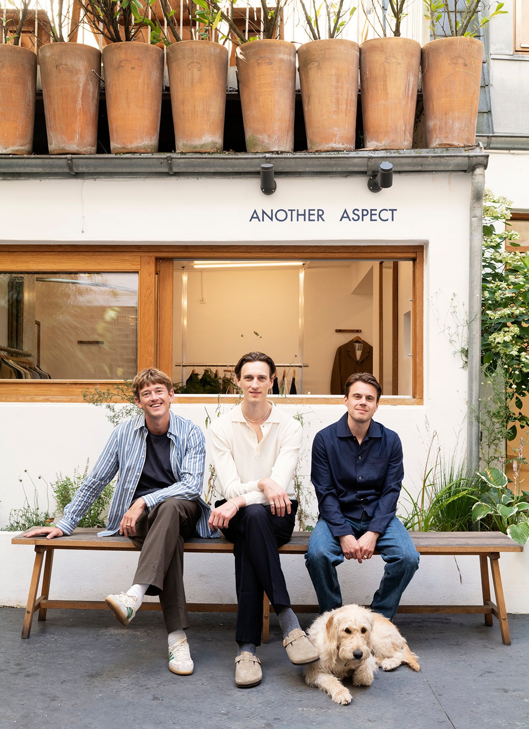 Anders Poulsen, Daniel Brøndt and Nicolaj Thomsen sitting on bench outside Another Aspect store in Copenhagen with dog