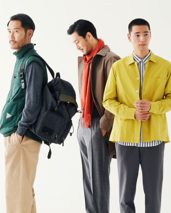 Three men modeling smart casual outfits including vests, jumpers, trousers, coats and backpacks.