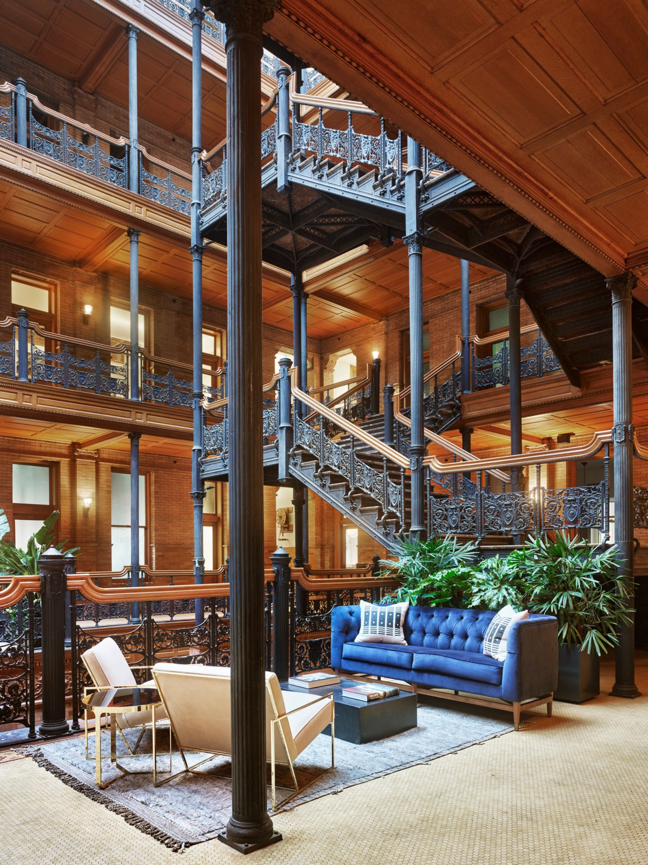 Interior of NeueHouse Los Angeles in the historic Bradbury Building showing ornate ironwork and natural lighting